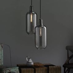 three glass pendant lights hanging from the ceiling above a table with two tea kettles on it