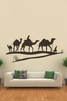 a living room with a couch and wall decal depicting three camels in the desert