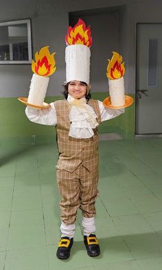 a little boy dressed up as a chef holding two cakes with flames on each one