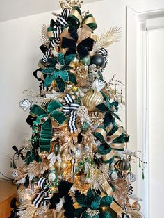 a christmas tree decorated with green, gold and black ribbons is shown in this image