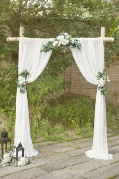 an outdoor wedding ceremony with white flowers and greenery