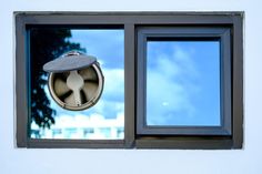 an air vent on the side of a building next to a window with a blue sky in the background