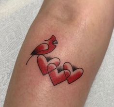 a couple of hearts with a bird on top of them tattooing it's arm