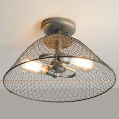 a light fixture with chicken wire hanging from it's center and two lights on each side