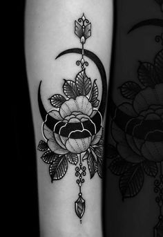 a black and white photo of two roses on the arm, one with a crescent