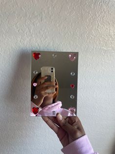 a person holding up a mirror with hearts on it