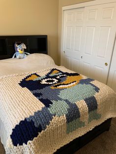 a bed with a blanket on top of it and a stuffed animal next to it