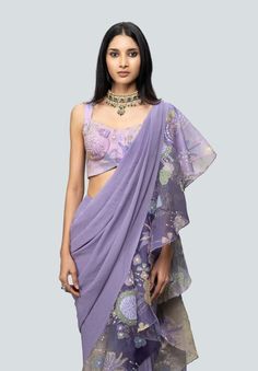 a woman wearing a purple sari with floral print on the top and bottom, standing in