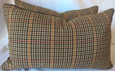 two brown and black plaid pillows sitting on top of a white bed sheet with the same pattern