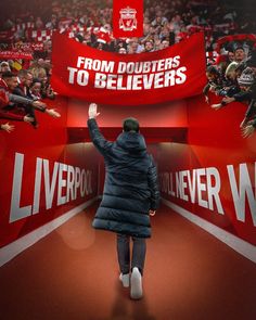 a man in a blue coat is walking towards a red sign with the words liverpool written on it