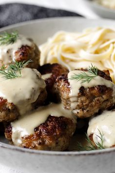 meatballs covered in white sauce and garnished with fresh herbs, served with pasta