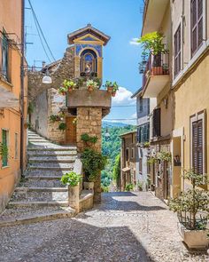 an alleyway with stone steps leading up to buildings and potted plants on either side