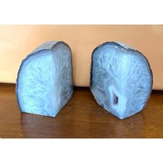 two pieces of blue fruit sitting on top of a wooden table next to each other