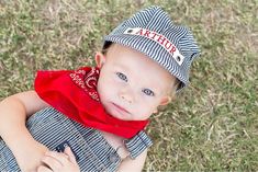 a young boy wearing a hat and scarf on top of his head in the grass