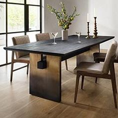 a dining room table with chairs, candles and vases on the end shelf in front of it