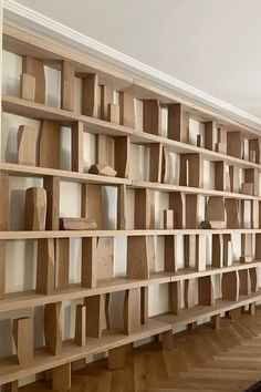 a wooden book shelf with many books on it in a room that has hard wood floors and white walls