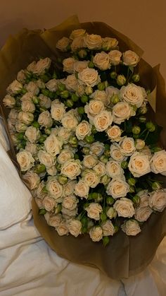 a bouquet of white roses sitting on top of a bed