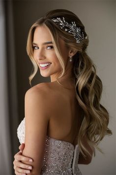 a woman with long hair wearing a bridal headpiece and smiling at the camera