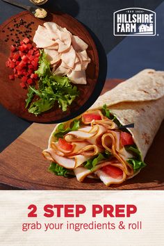 a wrap with meat, lettuce and tomatoes on it next to a cutting board