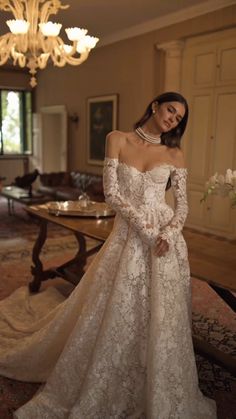 a woman in a wedding dress standing next to a chandelier