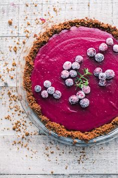 a pie topped with crumbs and powdered sugar sits on a white surface