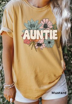 Auntie Shirt, Comfort Colors®, Floral Auntie TShirt, Flower Graphic Tee, New Aunt Gift, Pregnancy Announcement, New Baby Gift for Sister SIZE UP for an OVERSIZED FIT (see size chart in listing photos). Our shop uses direct-to-garment printing to make our products. The design ink is sprayed on, then allowed to soak into the fibers of the garment. This process yields fine quality prints and a smooth finish on the garment. COMFORT COLORS Garment-dyed t-shirt, made 100% with ring-spun cotton. The soft-washed, garment-dyed fabric brings extra coziness to your wardrobe while the relaxed fit makes it an excellent daily choice. The double-needle stitching throughout the tee makes it highly durable while the lack of side-seams helps the shirt retain its tubular shape. Relaxed Fit CARE Machine Wash Yellow Short Sleeve T-shirt For Family Matching, Casual Yellow Tops With Name Print, Cute Relaxed Fit Tops With Name Print, Yellow Cotton Tops With Name Print, Yellow Short Sleeve T-shirt With Name Print, Yellow Short Sleeve Top With Name Print, Spring Family Cotton Tops, Spring Cotton Tops For Family Occasions, Family Summer T-shirt With Name Print