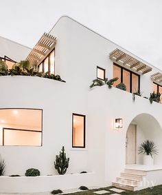 a white house with plants on the windows