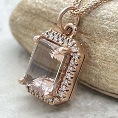 a necklace with an amethorate and diamonds on it sitting next to a rock