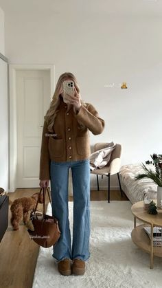 a woman is taking a selfie in her living room while holding a handbag