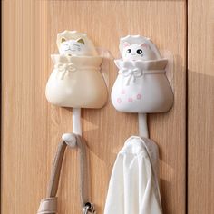 two white cats are hanging on the door knobs and one is holding a purse