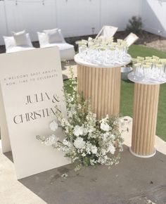 there is a table with wine glasses and flowers next to a sign that says julia & christian