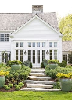 an advertisement for french doors in front of a house with potted plants on the lawn