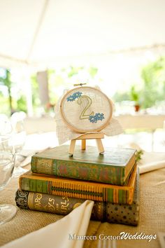 the table is set with books, glasses and a cross - stitch clock on it