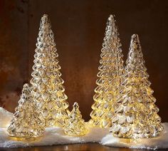 three clear glass christmas trees sitting on top of snow