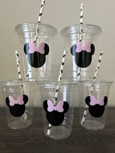 six cups with minnie mouse straws in them sitting on a wooden table next to each other