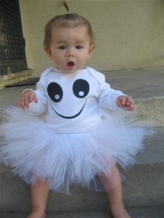 a baby girl wearing a white dress with a smiley face on it