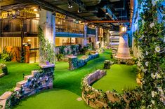 the inside of a building with artificial turf and plants on it's walls, as well as an indoor golf course