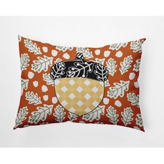 an orange pillow with a black and white crest on the front, surrounded by leaves