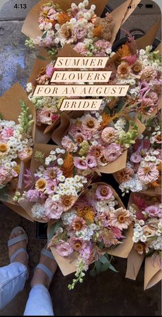 a bunch of flowers sitting on top of a table next to someone's feet