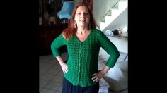 a woman standing in front of a couch wearing a green sweater