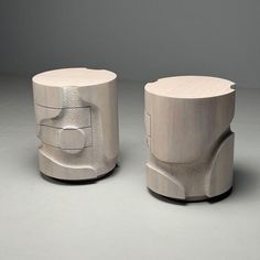 two silver stools sitting side by side on a gray surface, one is made out of wood