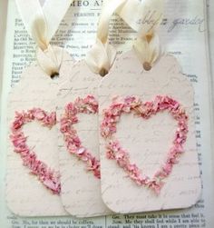 two tags with the word love written on them and flowers in the shape of hearts