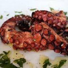 two octopus rings sitting on top of a white plate covered in sauce and parsley