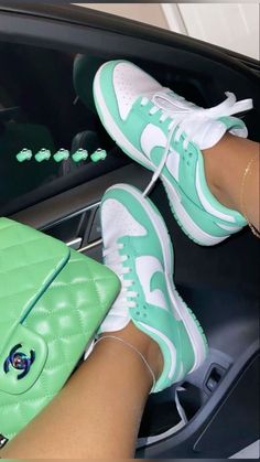 a woman's feet sitting on the dashboard of a car, holding a green purse