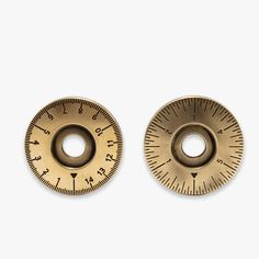 two brass dials on white background with one showing the scale and the other pointing in opposite directions