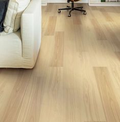 a white couch sitting next to a wooden floor in a living room on top of a hard wood floor