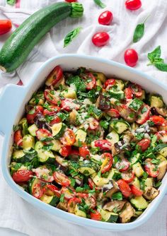 a casserole dish with zucchini, tomatoes and other vegetables