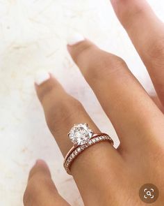 a woman's hand with a diamond ring on top of her finger and the other hand holding an engagement ring