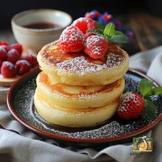 a stack of pancakes with powdered sugar and raspberries