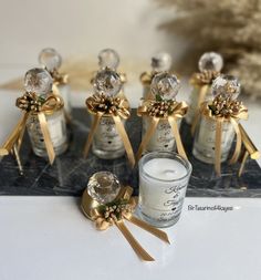 several small glass bottles with gold bows on them next to a candle and some candlesticks